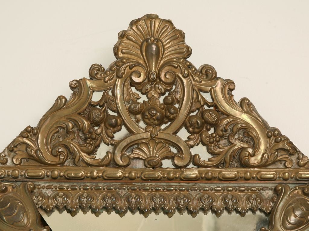Louis XIV style ornate mirror with a pressed tin frame, beveled center mirror and the canted side mirrors are wavy and we think they are made from mercury glass-look at the reflection in the detail photos.