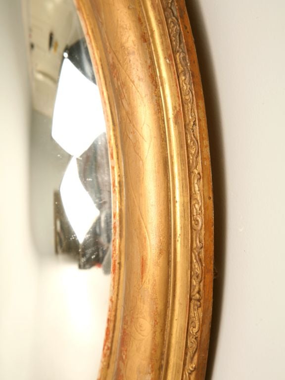 Louis Philippe mirror with an oval convex mercury glass mirror and a subtle floral carving around the gilded frame. This is an extremely rare item and the only one we have had in 15 years.