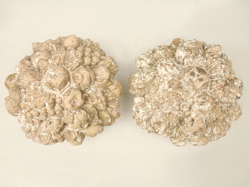 Pair of terra cotta fruit and flower finials. The abundant fruit and flowers overflow from a mellon shaped basket. They retain their original finish and patina. The diameter below is for the base the top is 16