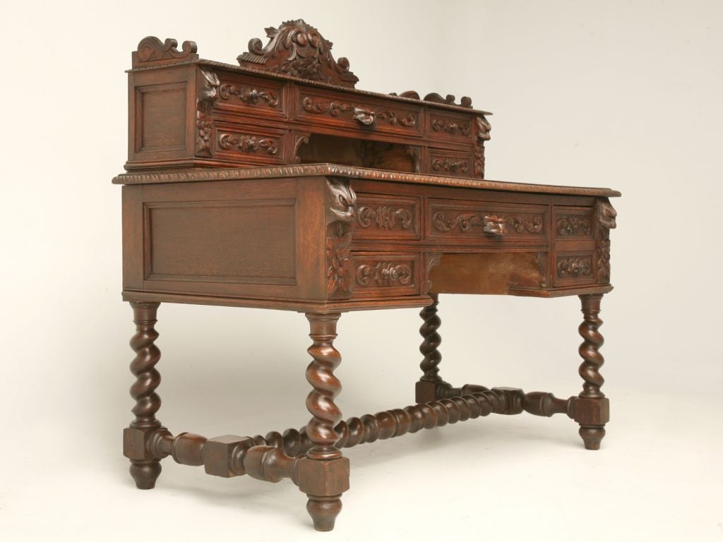 Heavily hand-carved solid French oak Henri II style desk with a sliding writing panel (image 9) for infinite leg space, a cash drawer, built-in lock box (image 10), hand-dovetailed drawers and barley twist legs and stretcher.