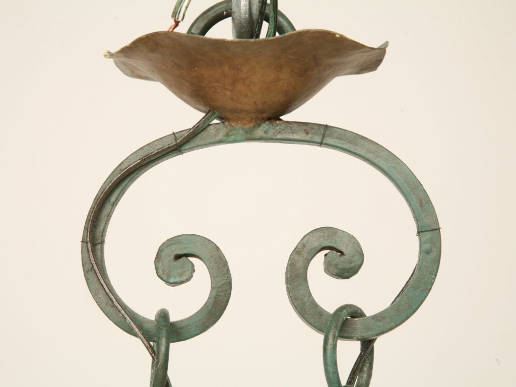 Vintage country French wrought iron chandelier with a beautiful patina and an unusual shape that would fit perfectly above a kitchen island. There is a pair of matching sconces available.