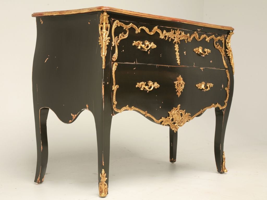 Reproduction Louis XV style 2-drawer commode with distressed black lacquer finish, gold leaf detailing and ormolu; great quality and style at an affordable price.