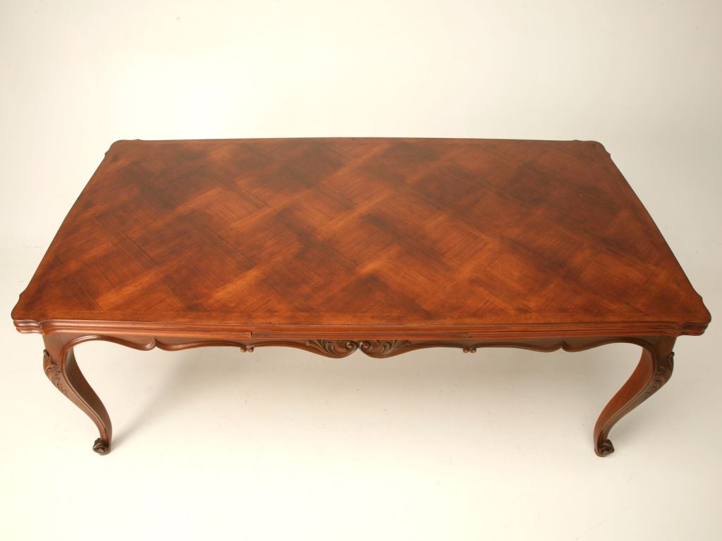 Louis XV style French walnut draw leaf table with a parquet top, hand-carved acanthus detail on the knees of the table and escargot feet. This table can seat 12 people comfortably. Only once every 5 years we find a French draw leaf table in this