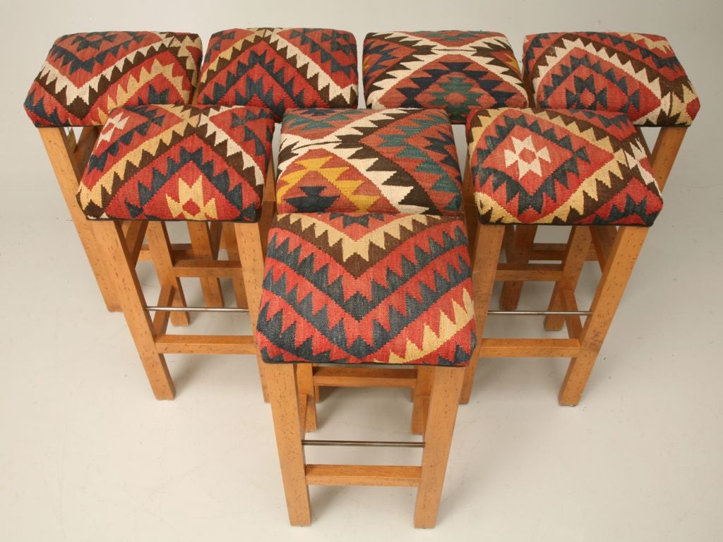 Stunnning set of six custom bar stools made from solid American hardwood and antique kilim rugs. The seats came from an antique kilim rug that had holes too bad to repair. In order to salvage the rug we made them into seat coverings and other