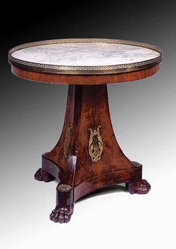 # P532 - Empire gueridon having a round white marble top with a pierced brass gallery above a narrow mahogany frieze. All raised on a beautifully figured mahogany tapering concave triangular base enriched embellished with gilt ormolu mount of a lyre