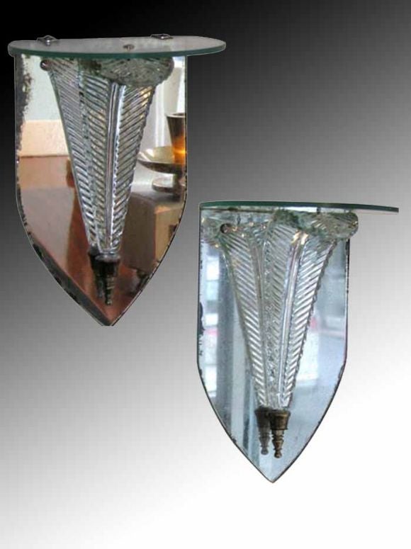 Grosfeld House crystal plume wall brackets. The shield shaped mirrored back plates with a cut crystal graceful curved feather supporting a half round glass shelf. The simple playful decorative design is typical of clean elegant “modern”  1940's