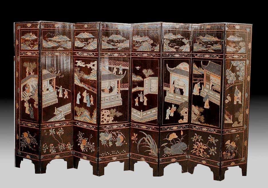 A Chinese corromandel lacquer eight fold screen having a black background with incised polychrome decoration. The stylized  floral border framing landscaped panels above and foliage panels below. All framing a central scene of temples in a garden