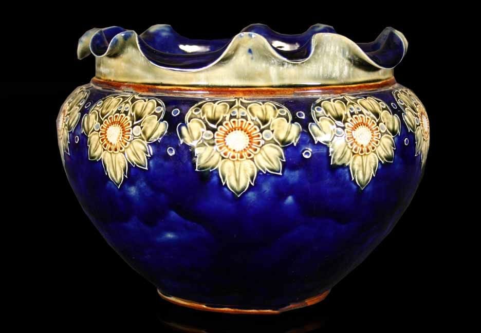 # F566 - A pretty Doulton Lambeth jardiniere having a deep blue background which is delicately painted with stylized flower motifs. The graceful scalloped rim is quite unusual which is above the elegant ovoid shaped body. The famous Doulton pottery