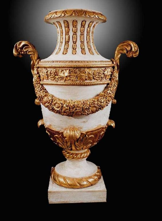 Neoclassical parcel gilt and painted urn of amphora form with a flat rim and scroll handles. Note the superb carving on the floral garland swags with their carefully detailed flowers. The tapering neck with inset panels filled with carved and gilded