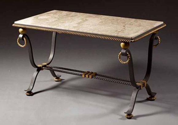 Occasional table having a rectangular marble top surrounded by a rope twist molded metal frame and raised on a stylized 