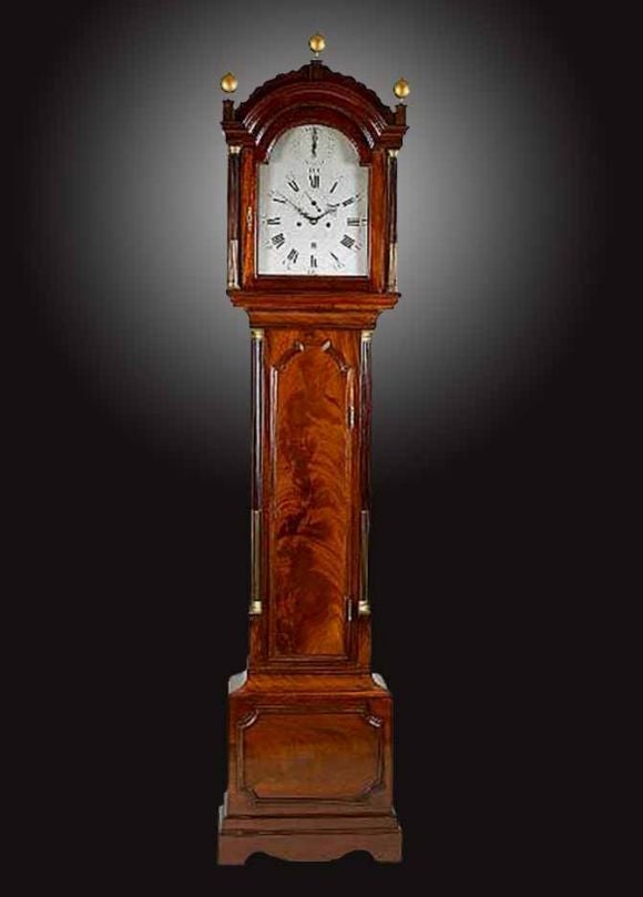 Late Georgian mahogany long case clock by Wm. Stevenson, Maidstone. The break arch hood surmounted by a scalloped border and gilt finials above brass mounted stop-fluted columns, flanking a 12 inch signed silvered dial with calendar aperture,