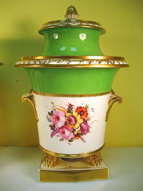 A pair of finely made Coalport fruit coolers raised on a platform and paw design supports. The expertly painted floral arrangements are placed in a pure white background on both faces of each vase, and also on the lids, and bordered by gilding and 