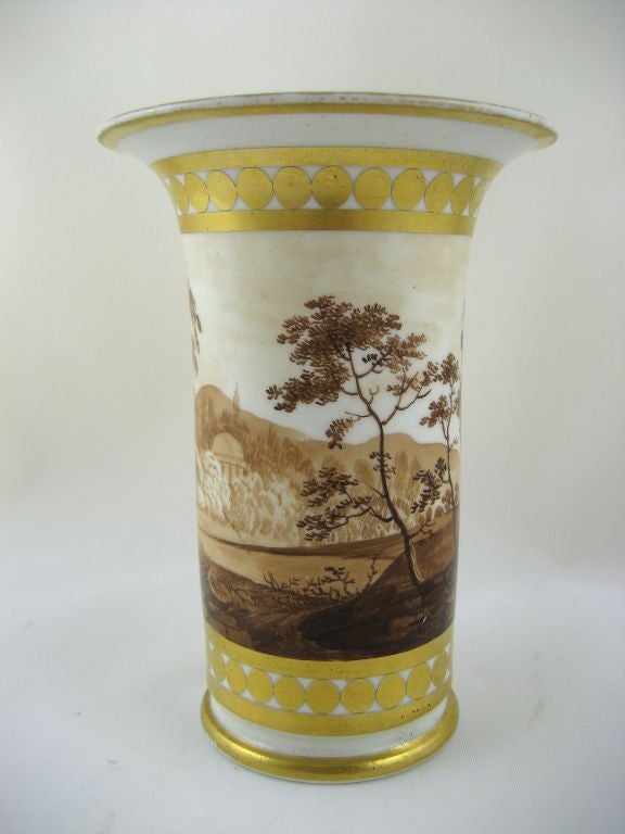 A beautiful petite trumpet vase by Chamberlain's Worcester, also known as a Spill Pot. The piece is painted with a landscape featuring ruins, all applied in a sepia-tone palate. The scene is bordered by bands of gilt design, contrasting nicely with