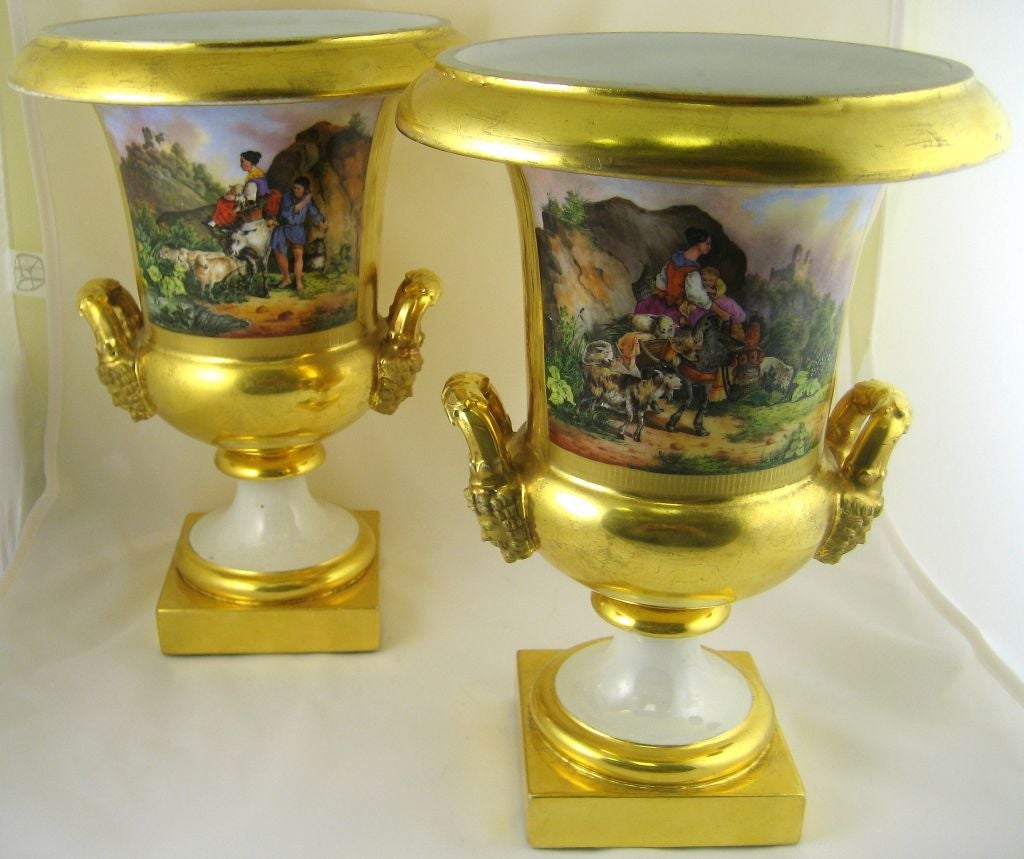 A stunning pair of French Empire Paris porcelain vases, in a stepped Campana form. Embellished with a solid gilt ground with incised and shaded design-work, that has a focal point in the superb landscape scene on each piece. The scenes depict, in