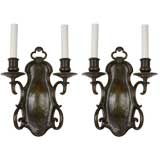 A pair of dark bronze two arm sconces by the E. F. Caldwell Co.