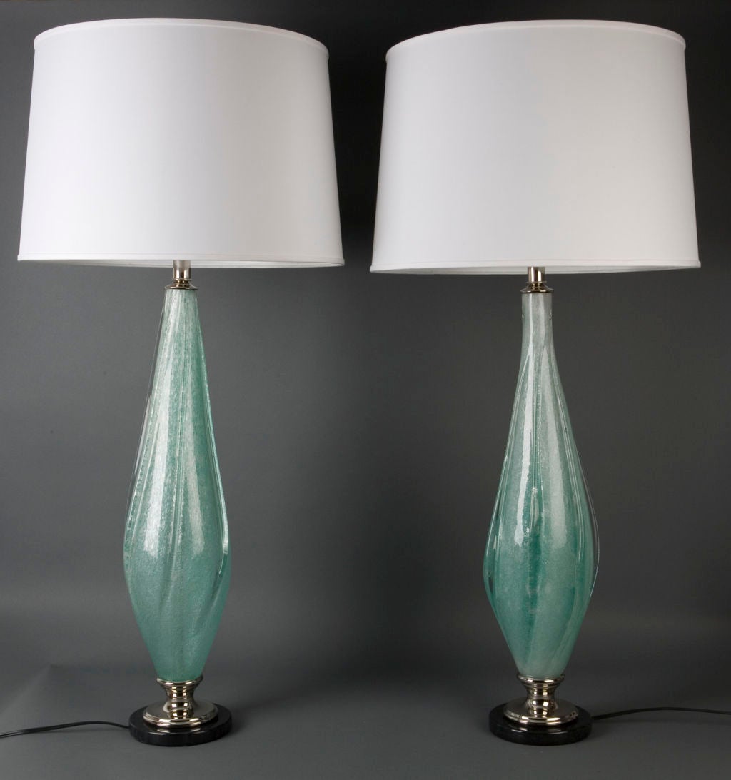 ATL1731<br />
<br />
A pair of blue iridescent murano glass lamps having nickel fittings on black marble bases. Shades not included.<br />
<br />
Overall height: 40 1/2