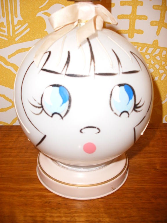 ROUND GLASS GLOBE FACE - GIRL OR DOLL FACE WITH PAINTED BIG BLUE EYES, PINK MOUTH AND HAIR IN BANGS.