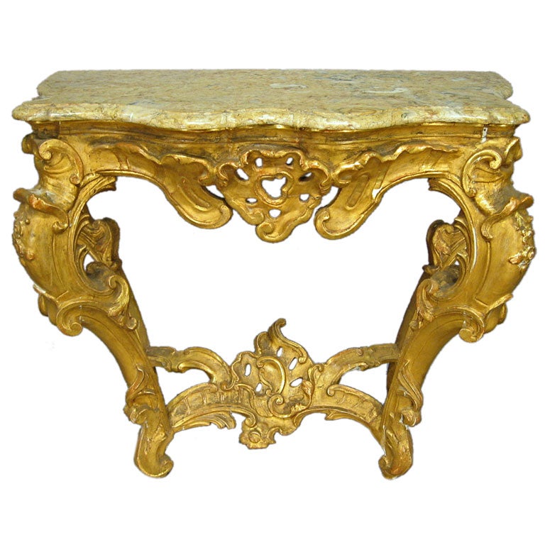 A fine Gilt-wood console table, the Rococo serpentine frame mounted with a conforming mottled beige marble top. Dating from the mid 1700s, and Italian in Origin. 

The console has muscular The legs in reverse-cabriole form, constructed with