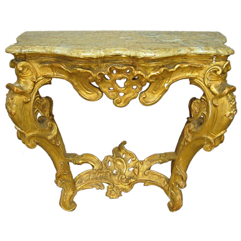 A fine Gilt-wood console table, the Rococo serpentine frame mounted with a conforming mottled beige marble top. Dating from the mid 1700s, and Italian in Origin. 

The console has muscular The legs in reverse-cabriole form, constructed with
