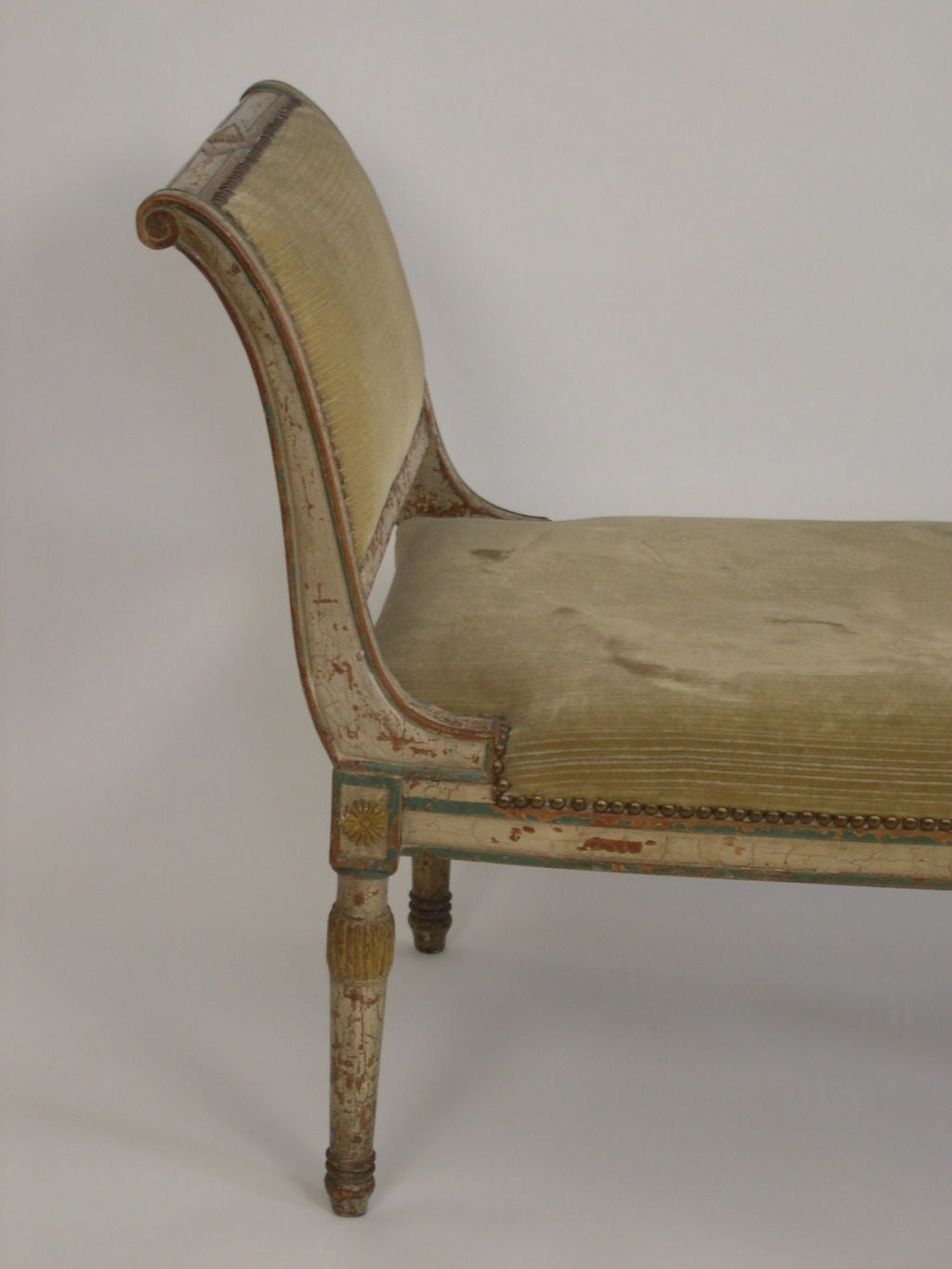 Directoire period diminutive recamier in walnut or beech, with carved neoclassical decoration, retaining its original painted blue, cream and yellow decoration.