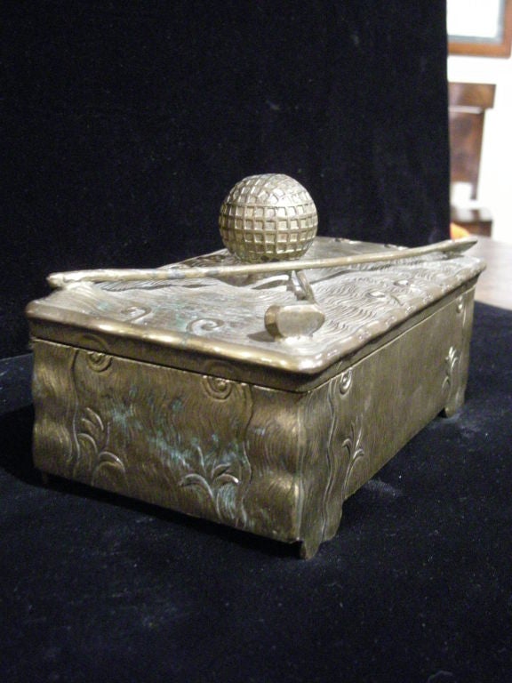 Arts & Crafts period brass cigar (?) box by Jennings Brothers with floral decoration and well modelled golf ball and clubs, lined with mahogany, impressed 'JB' mark on bottom.
