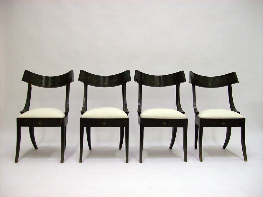 Ebonized klismos chairs with anthemia and scrolling vine painted designs.