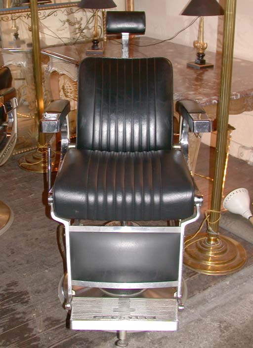 A barbers chair by Belmont in chrome metal and black leatherette, pivoting, adjusting height and swiveling mechanism. Measures low and folded.