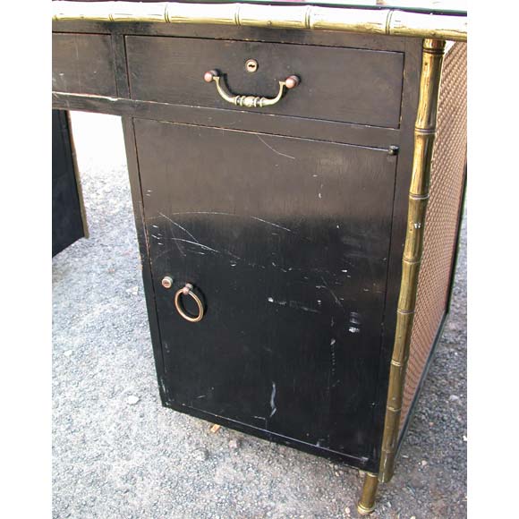 A black lacquered wood desk with a bamboo brass frame and legs the front and sides have a caned façade. It has three upper drawers and two side cupboards with six adjustable shelves in total and a black opaline plateau.