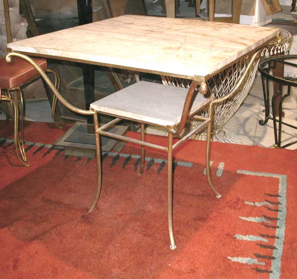 A two-tiered square table by René Drouet with a gold leaf wrought iron frame and center lower and top travertine plateaus.