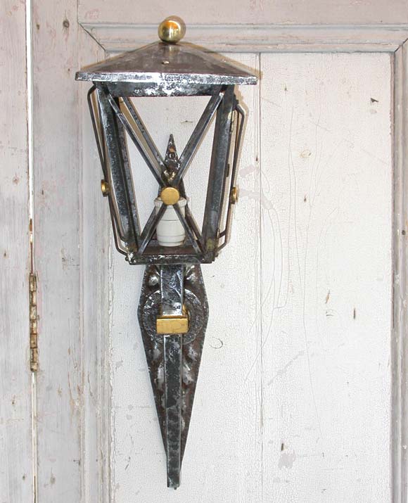 A pair of lantern wall light appliques in polished wrought iron with partial gilt decor, one side opening pane door, one upper interior light and brass ball top finial.