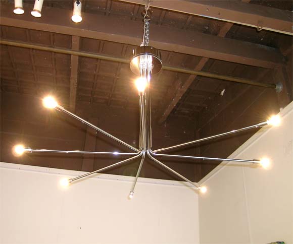 A 1970's Italian ceiling light in chrome metal with a round ceiling ring holding eight think chrome tubes bending out to a star with small 12 V halogen lights.