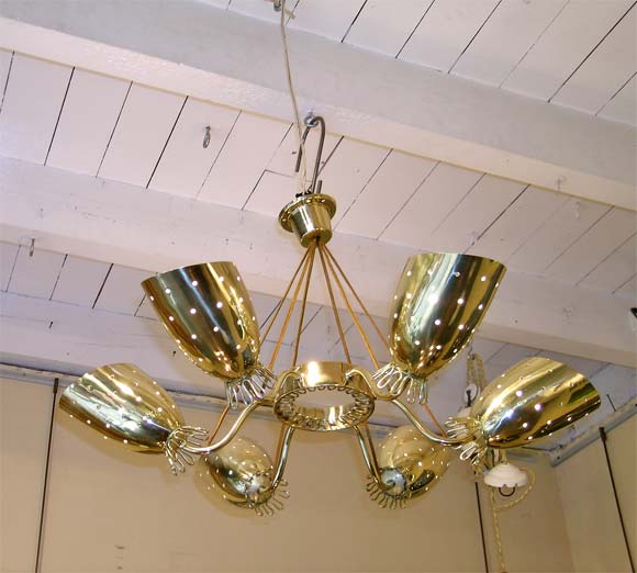 A ceiling light in brass, ceiling ring holding electric cables and central ring with looped decor and six branches holding loop decor perforated base shades.