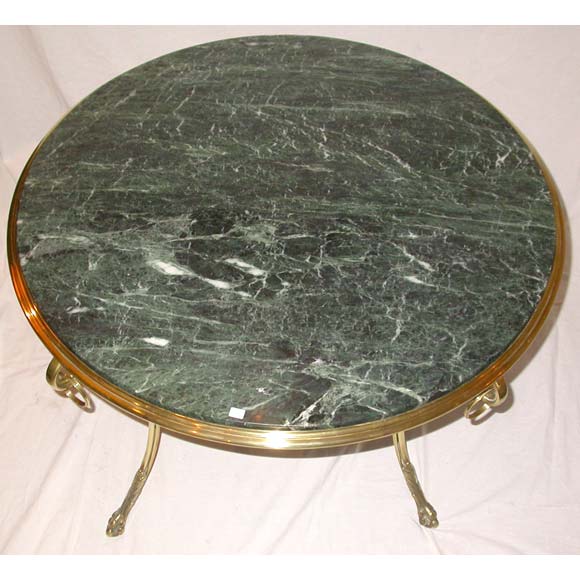 A round coffee table with a bronze and brass frame on scrolled top legs with ring finials ending in ball and claw sabots, a grooved hoop stretcher and a green 