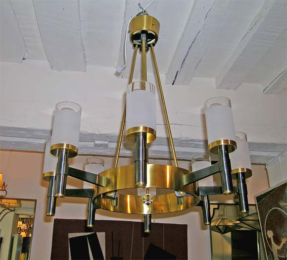 A ceiling light by Raymond Subes in a duo of canon and gilt bronze, a ceiling ring with four ends holding a large gilt bronze ring with eight canon torch like branches with sand blasted glass cups with clear tops.