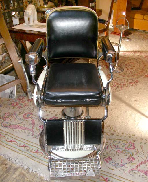 A Belmont adjustable 1948 barber's chair, pivoting descending central column stand, pedal handle to rise, a chrome iron, ceramic and metal frame, black leatherette back, seat cushion and foot rest back.