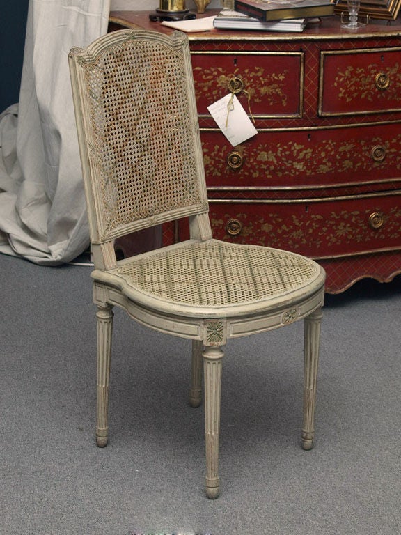 Set of 6 cane, carved and painted, Louis XVI style dining room chairs.  The chairs were fashioned in Atelier Jansen in Paris and are marked with the Jansen logo.  The cane is stenciled with a cross hatch pattern. The seat of these chairs is wide