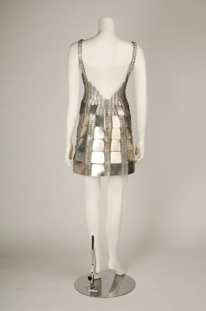Classic Late 1960's Paco Rabbane<br />
Metal gladiator style mini dress. Tank shaped bodice constructed of small molded aluminum disks and has contoured bra top.  Skirt is made of same aluminum disks with sections of square aluminum plates forming