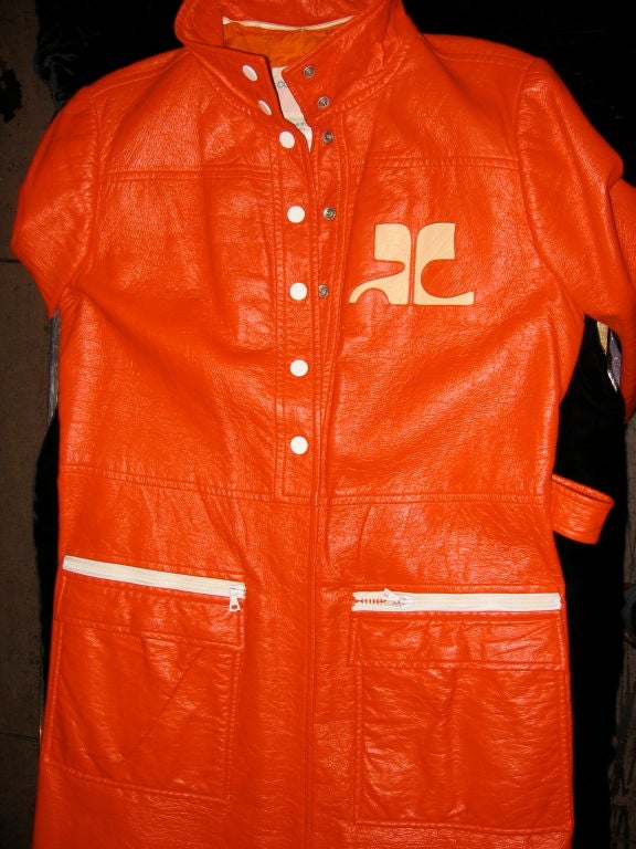 please check measurements for size.<br />
<br />
Orange Vinyl Coat – Classic Courrèges initials on left breast, white zippers on two front pockets. 7 white snaps down front to waist. Two white snaps on each cuff. Back slit from waist to hem.