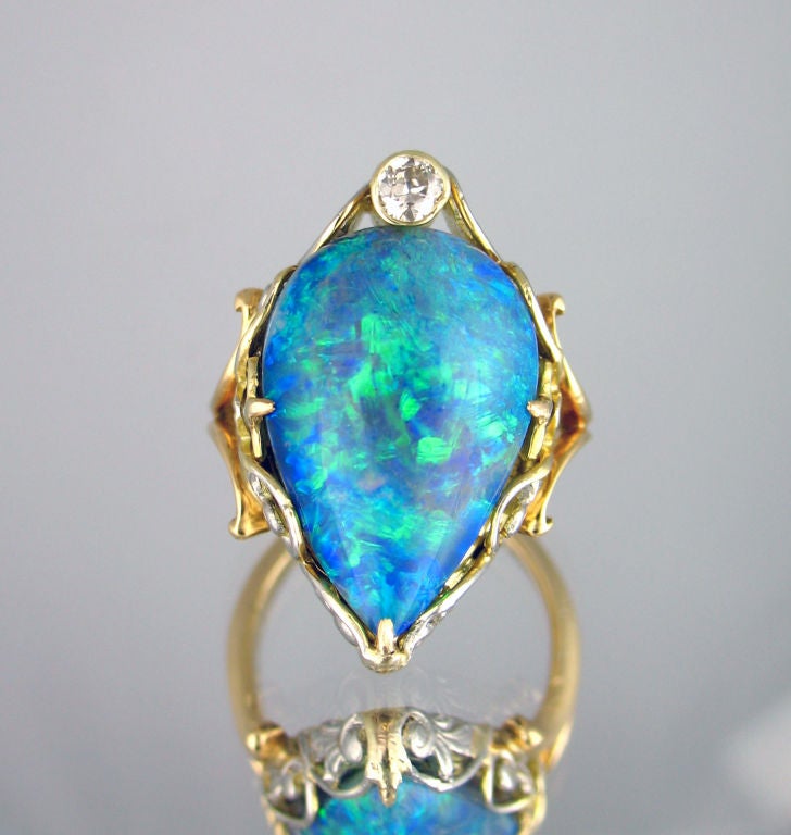 18 karat yellow and white gold Art Nouveau ring set with one pear shaped cabochon black opal and one Old Mine Cut diamond weighing approximately 0.12 carat.  Opal measures 18.70mm x 12.68mm x 6.71mm.  Possibly Marcus and Company.