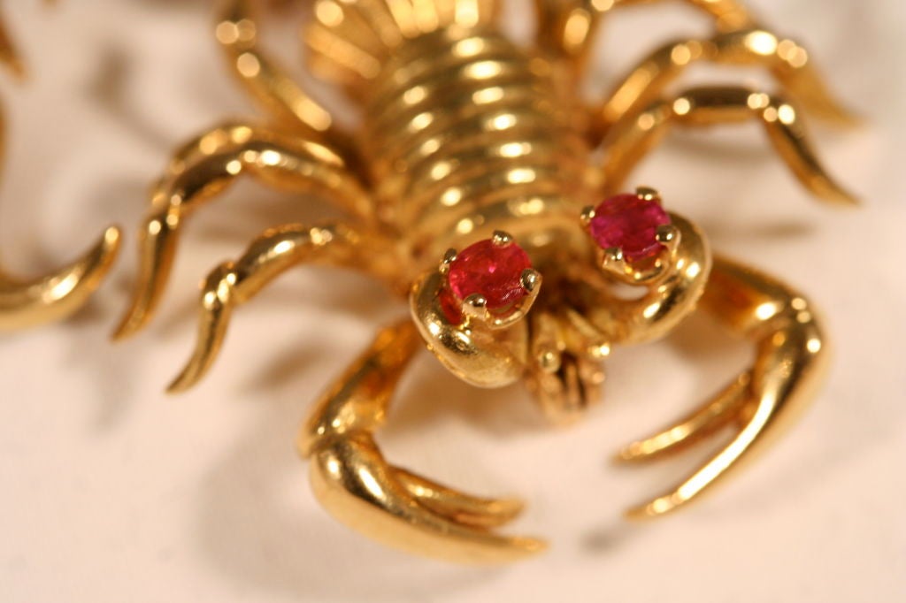 Highly stylized 18K gold articulated Scorpion pin. This French hallmarked Arachnid pin has prong set ruby eyes and an articulated tail and claws. It measures 1 1/2