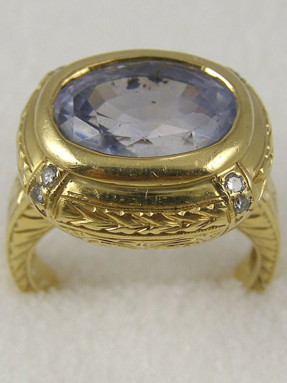 18K YG w/ 9x13mm oval light blue faceted natural sapphire bezel set in cushion shape with 2 diamond accents at each corner. Beautifully hand engraved on all sides. Stamped with Loree Rodkin hallmark LRG on inside of shank.

Stk #32735