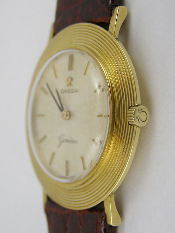 Omega 18K YG ultra thin dress model 32 x 36mm case circa 1960's with wide bezel with fine concentric rings. Signed recessed Omega crown. Original matte silver dial with gold applied indexes and Omega logo and matching hands . 17 jewel manual wind