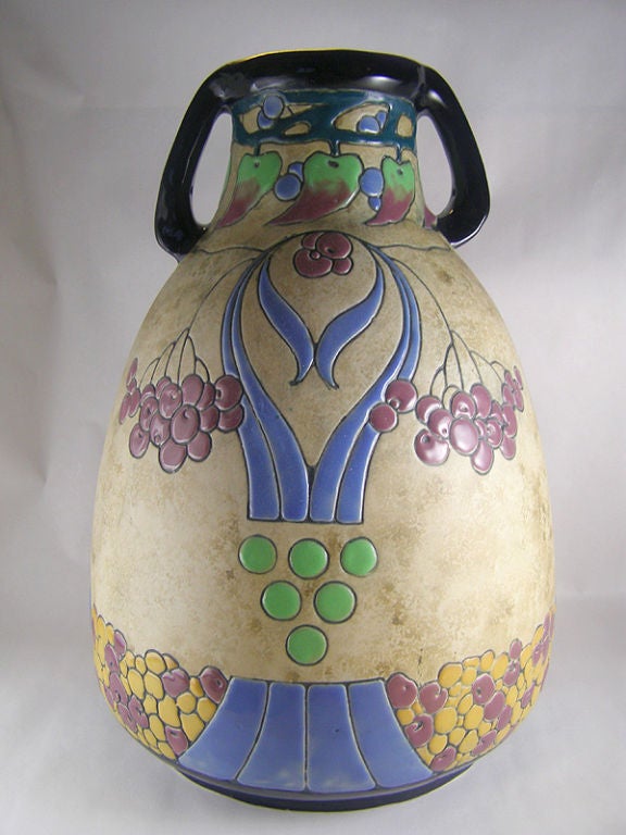 Amphora "Campina" series circa 1920's very large (16" high) vase in the Arts and Crafts style shaped as a tapered jug with 2 handles at the neck. Feauturing a large and majestic enamelled parrot perched on a branch with its wings