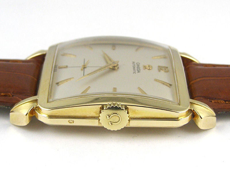 Omega 14K YG oversized square case with faceted wide gold bezel and large lobed lugs 33mm x 44mm circa 1950's with matte silver dial with gold applied indexes and pointy hands. Omega self winding movement with subsidiary seconds. Signed Omega crown.