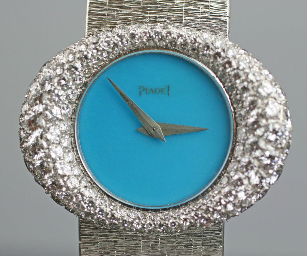 A beautiful lady's watch by Piaget, with a turquoise dial and an elliptical case with round brilliant cut diamonds.  The attached 18K white gold bracelet has a bark finish and a fold over clasp.