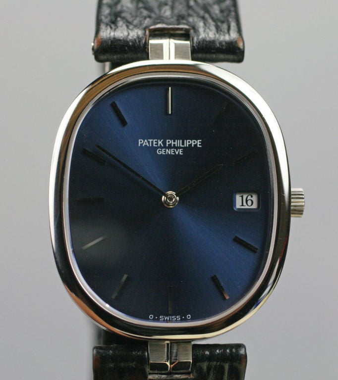 In excellent condition, this Patek Philippe reference 3930 is also referred to as the Ellipse, due to its shape. The beautiful dark blue metallic dial has a date window  at three 0'clock and a sapphire crystal.  It has decorative t bar lugs, black