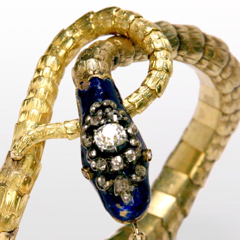 Victorian Period 18 karat gold blue enamel and diamond snake bracelet with diamond pendant hanging from mouth.  Body is realistically articulated with etched scales that undulate, with tail wrapping around head to form unique clasp.  Head