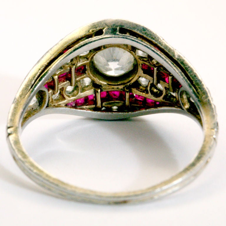 Diamond and ruby pinky ring with center bezel set white diamond.  Distintive design with bands of rubies alternating with diamonds in Art Deco style.