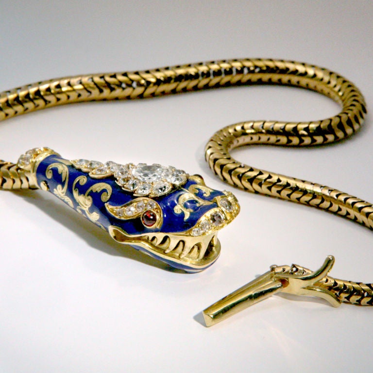 Fabulous serpent necklace with blue enamel and gold head featuring large center diamond surrounded by eleven smaller diamonds plus 26 other diamonds.  Ruby eyes.  Etched scroll work on underside of head.  Body is gold snake chain with end that forms