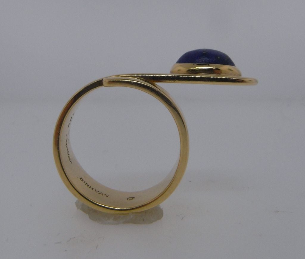 A very chic ring, being a spiralling length of gold wrapped around the finger and culminating in a cabochon lapis lazuli set to a collet mount.  The ring terminal is designed so as to sit part-way over the adjacent finger.  A Vietnamese born,